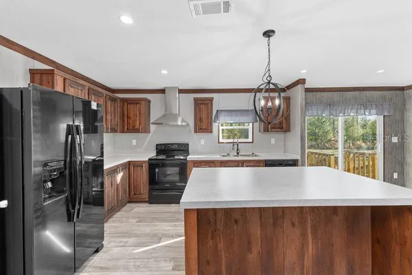 a kitchen with stainless steel appliances granite countertop a refrigerator a sink dishwasher a stove and white cabinets with wooden floor