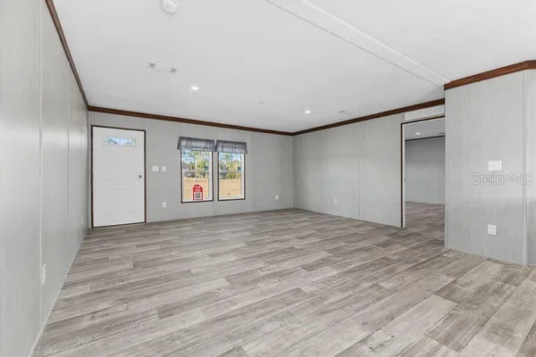 a view of an empty room with window and wooden floor