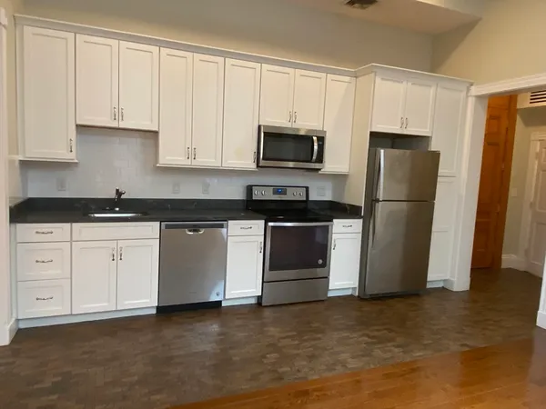 a kitchen with white cabinets white stainless steel appliances and refrigerator