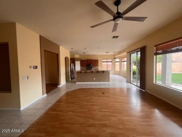 a view of an empty room with window and a kitchen