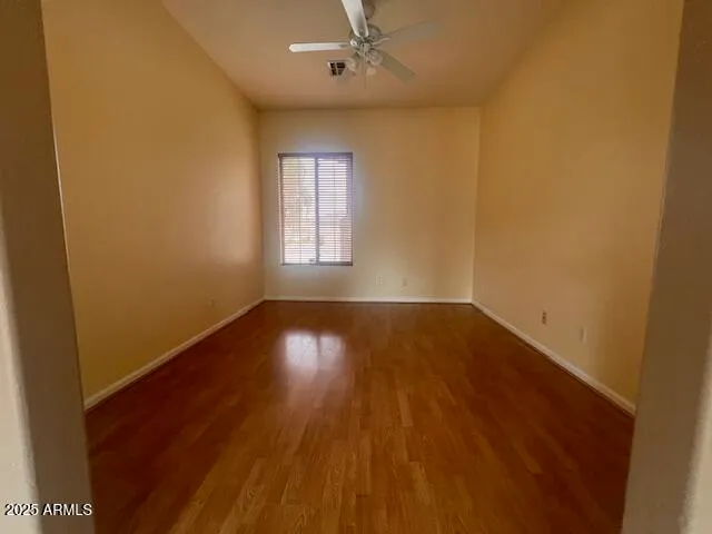 an empty room with wooden floor windows and fan