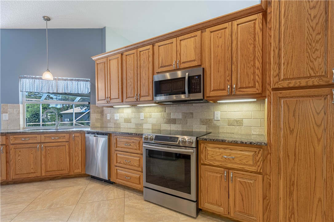 414 Ash Street Sebastian, FL 32958 - Photo 7 of 36 a kitchen with granite countertop wooden cabinets stainless steel appliances and a window