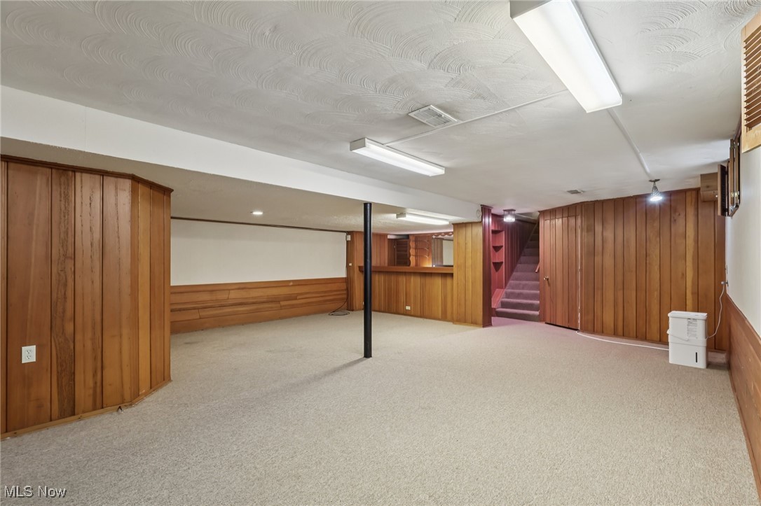 33300 South Woodland Road Cleveland, OH 44124 - Photo 38 of 50 Finished basement featuring wood walls, light carpet, and stairs