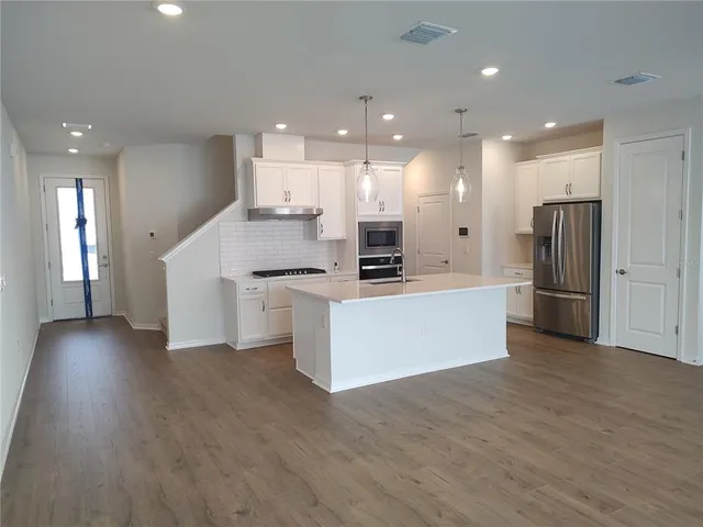 a large kitchen with stainless steel appliances kitchen island wooden cabinets and a granite counter tops