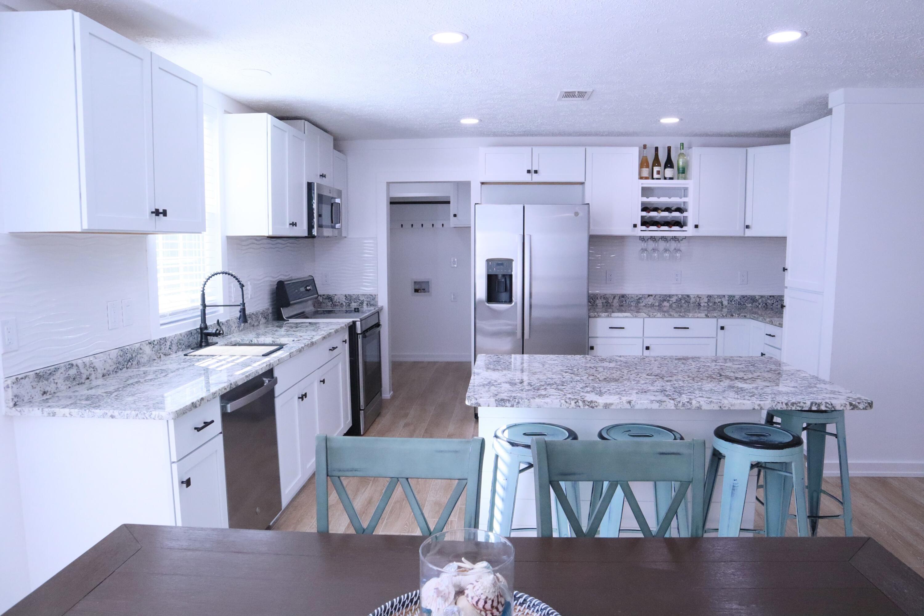 4608 Falcon Way Crestview, FL 32539 - Photo 7 of 42 a kitchen with kitchen island granite countertop a sink and refrigerator