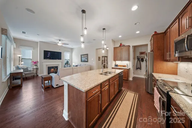 a large kitchen with stainless steel appliances kitchen island granite countertop a large kitchen island a stove a refrigerator a sink dishwasher a dining table and chairs with wooden floor