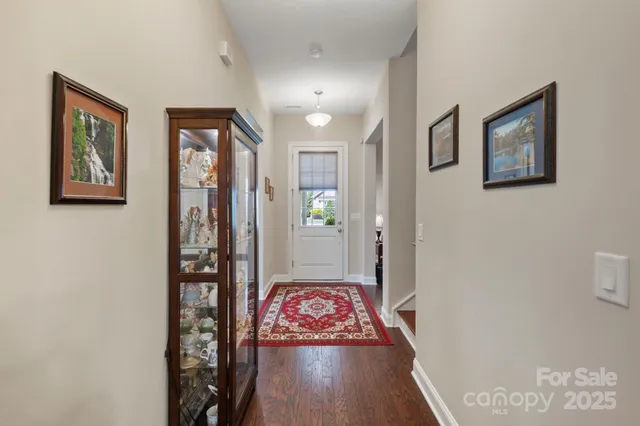 a view of a hallway with wooden floor and a bathroom