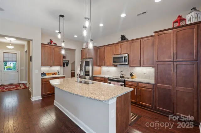 a kitchen with kitchen island granite countertop a sink appliances and cabinets