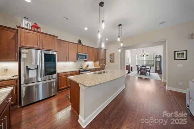 a large kitchen with granite countertop a large counter top a sink stainless steel appliances and cabinets