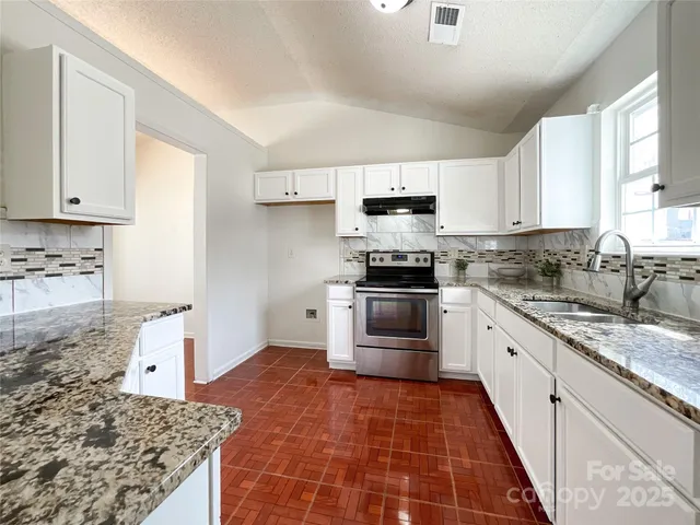 a kitchen with kitchen island granite countertop a stove a sink and a refrigerator