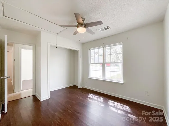 an empty room with wooden floor and a ceiling fan