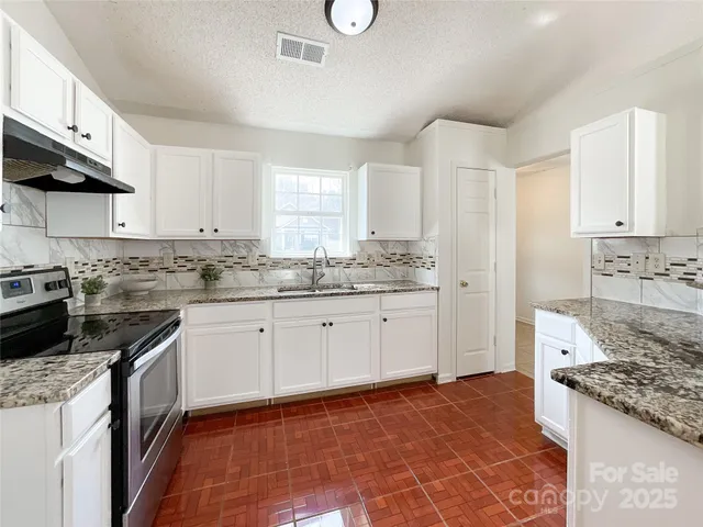 a kitchen with granite countertop a stove top oven sink and cabinets
