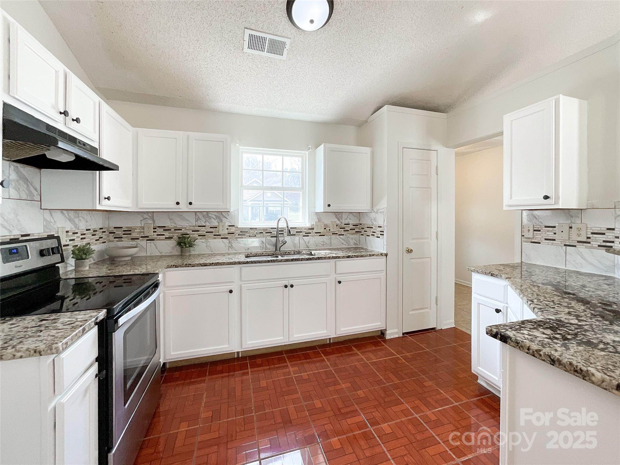 5610 Stone Bluff Court Charlotte, NC 28214 - Photo 10 of 41 a kitchen with granite countertop a stove top oven sink and cabinets