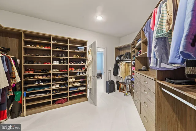 a view of walk in closet with clothes and shoes