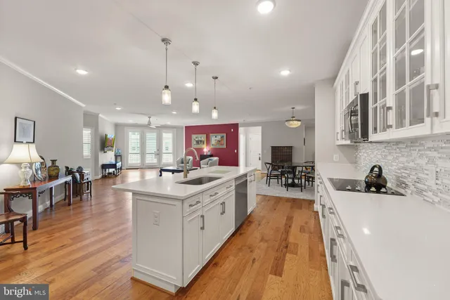 a kitchen with stainless steel appliances a sink a stove top oven a dining table with wooden floor