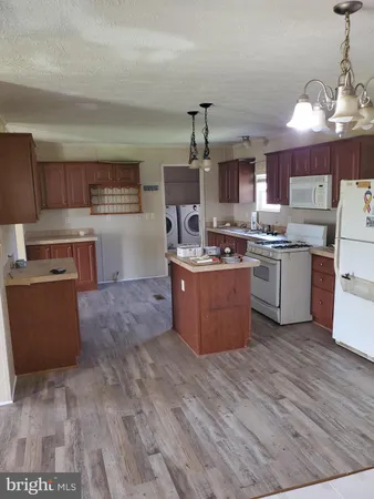 a kitchen with stainless steel appliances granite countertop a stove top oven a sink dishwasher and a refrigerator with wooden floor