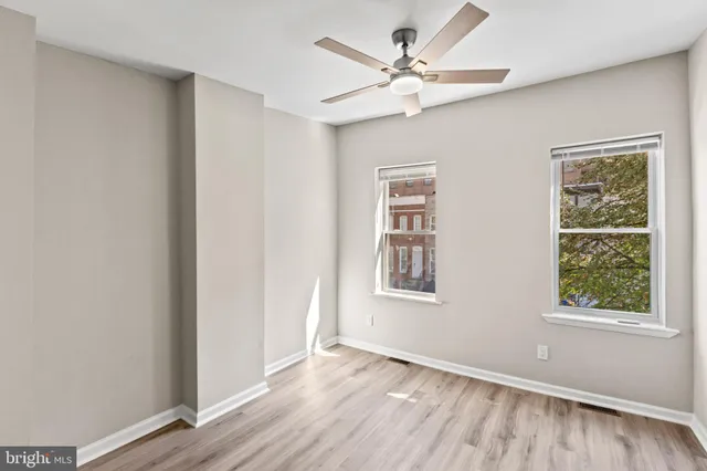 a view of an empty room with a window and wooden floor
