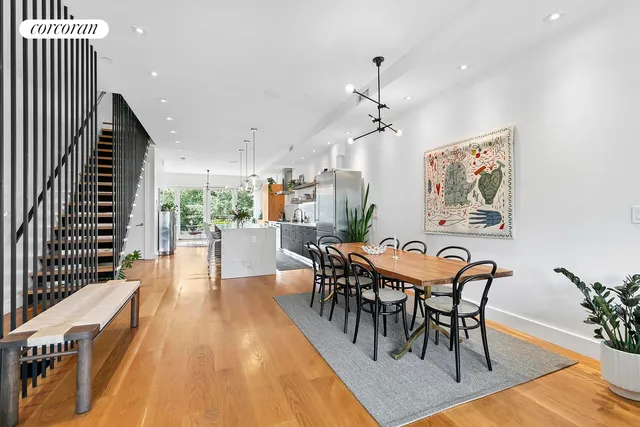 a kitchen with stainless steel appliances granite countertop a stove a sink dishwasher a microwave oven and a dining table with wooden floor