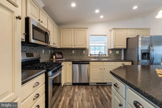 a kitchen with stainless steel appliances granite countertop a stove a sink and a microwave