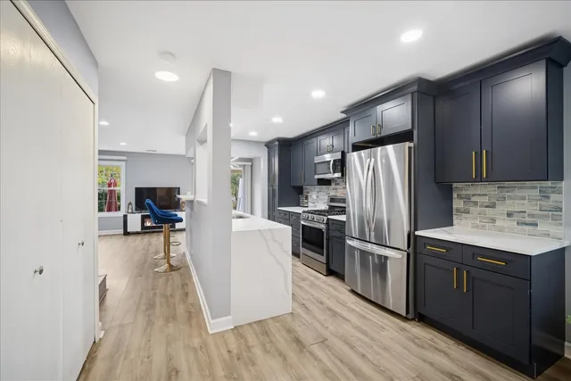 a kitchen with refrigerator a sink and wooden floor