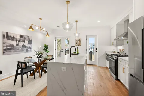 a large kitchen with cabinets a sink a stove and dining table with wooden floor