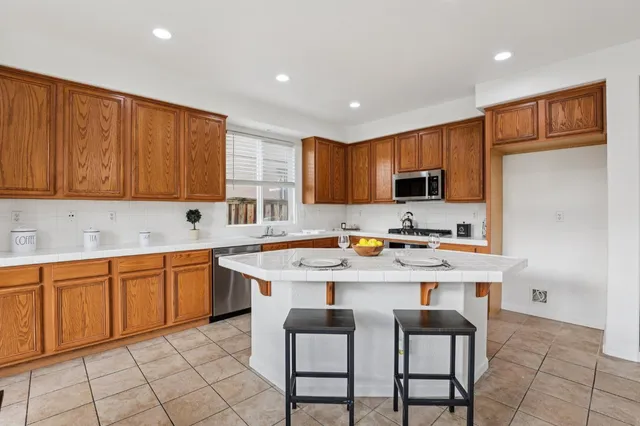 a kitchen with stainless steel appliances granite countertop a table chairs sink refrigerator and cabinets