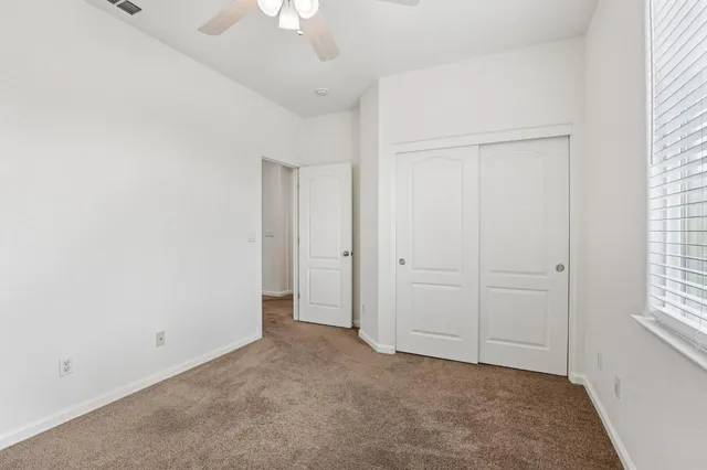 an empty room with windows and fan
