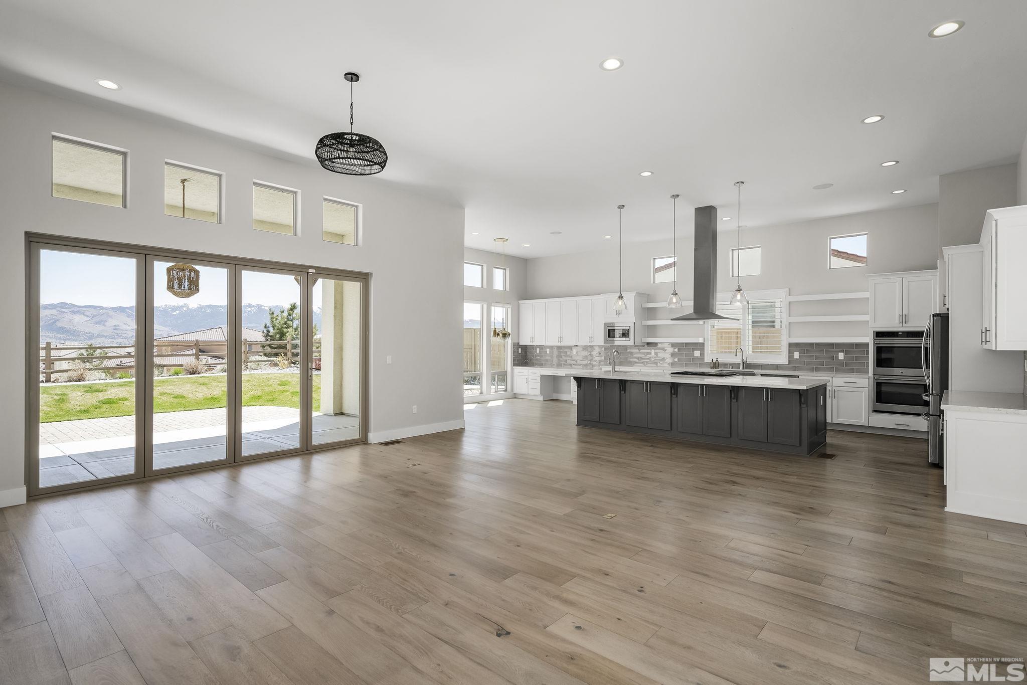 13326 Travertine Lane Reno, NV 89511 - Photo 5 of 36 a large white kitchen with large windows and wooden floor