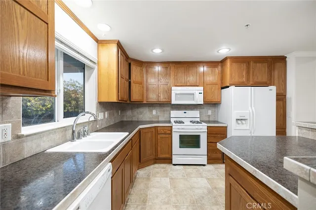 a kitchen with stainless steel appliances granite countertop a sink stove refrigerator and cabinets