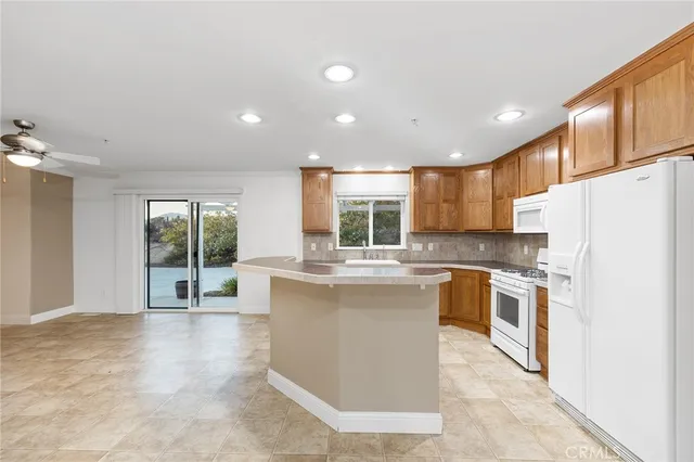 a kitchen with stainless steel appliances granite countertop a refrigerator a sink dishwasher a oven with white cabinets and wooden floor