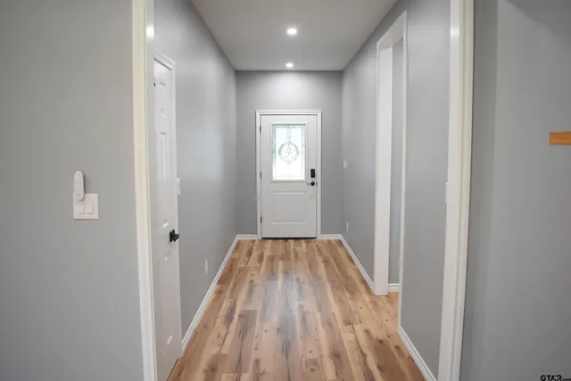 a view of a hallway with wooden floor and a bathroom