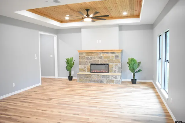 a view of an empty room with wooden floor and a fireplace