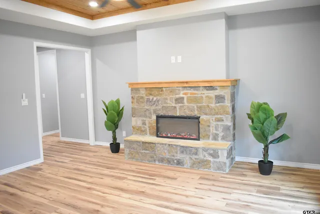 a living room with a fireplace and potted plants with wooden floor