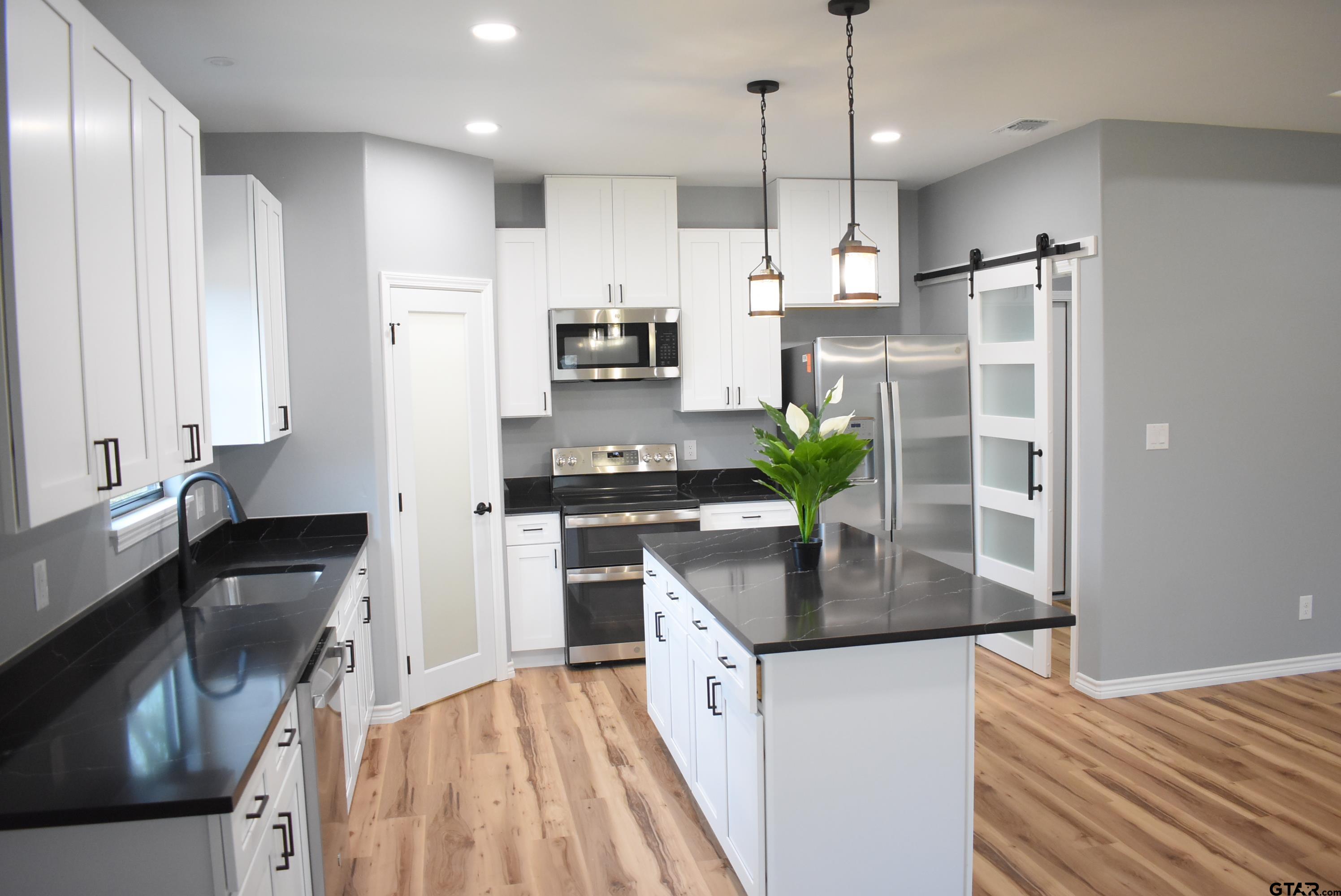 162 Ruby Lane Nacogdoches, TX 75965 - Photo 5 of 44 a kitchen with stainless steel appliances granite countertop a refrigerator a sink dishwasher a stove and white countertops with wooden floor