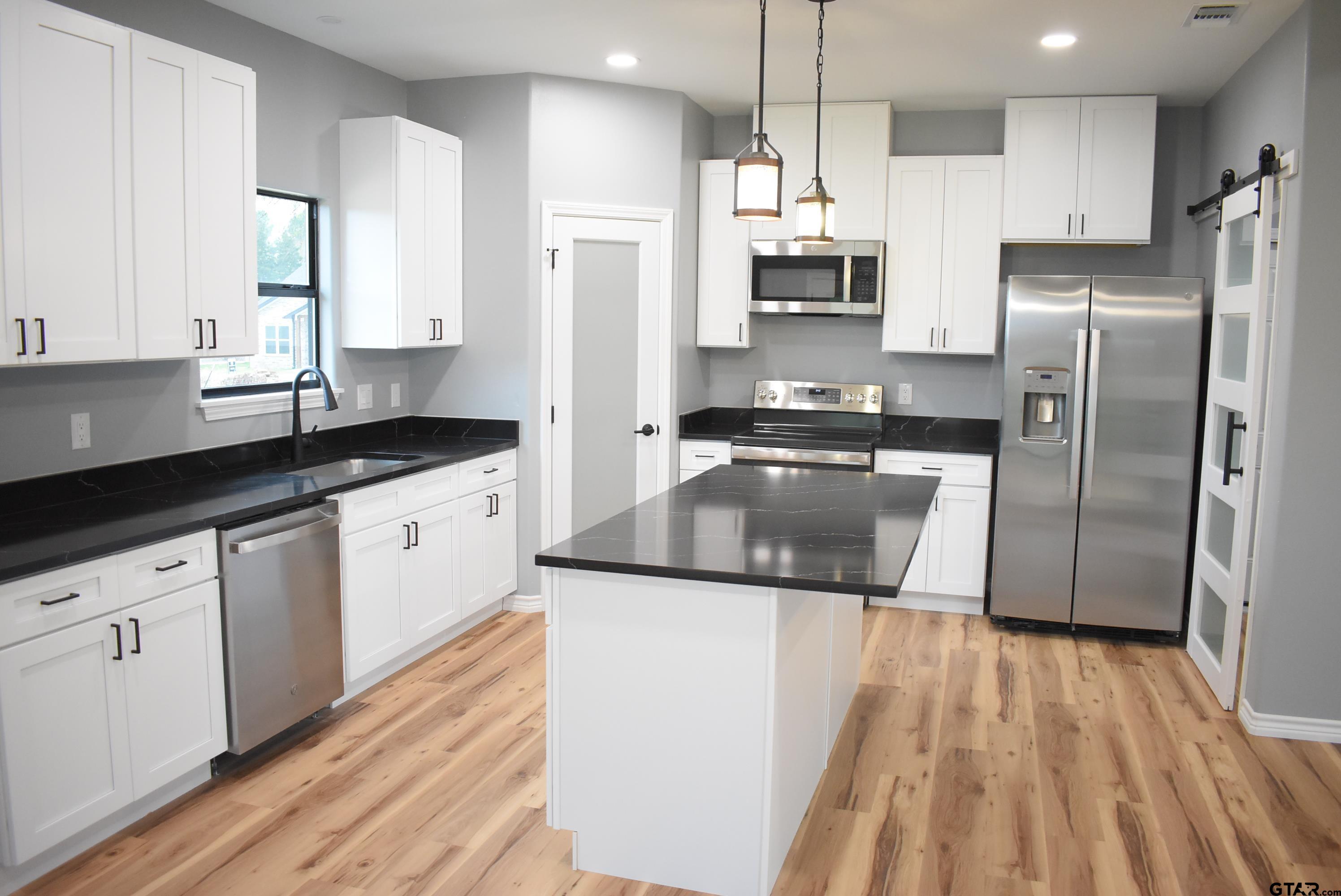 162 Ruby Lane Nacogdoches, TX 75965 - Photo 7 of 44 a kitchen with stainless steel appliances granite countertop a refrigerator a sink dishwasher a stove and white countertops with wooden floor