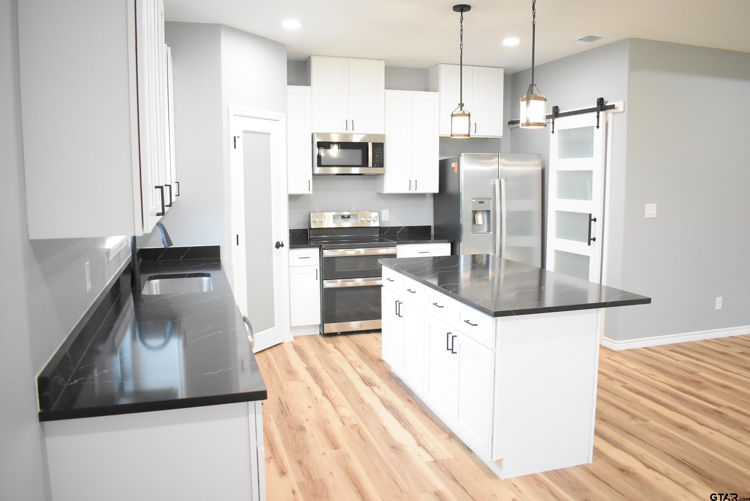 162 Ruby Lane Nacogdoches, TX 75965 - Photo 9 of 44 a kitchen with stainless steel appliances kitchen island granite countertop a refrigerator a stove and a sink with wooden floor