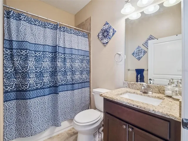 a bathroom with a granite countertop sink mirror vanity and toilet