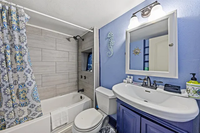 a bathroom with a sink a toilet a mirror a bathtub and shower