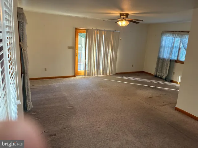 an empty room with a window and a ceiling fan