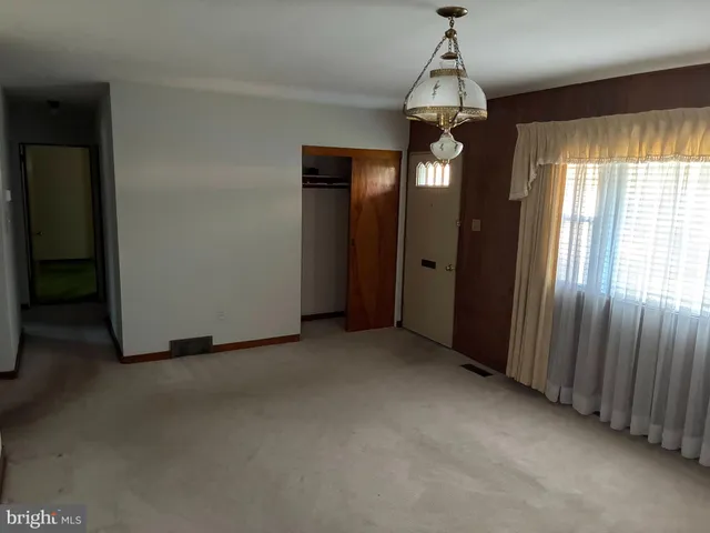 an empty room with chandelier fan and windows