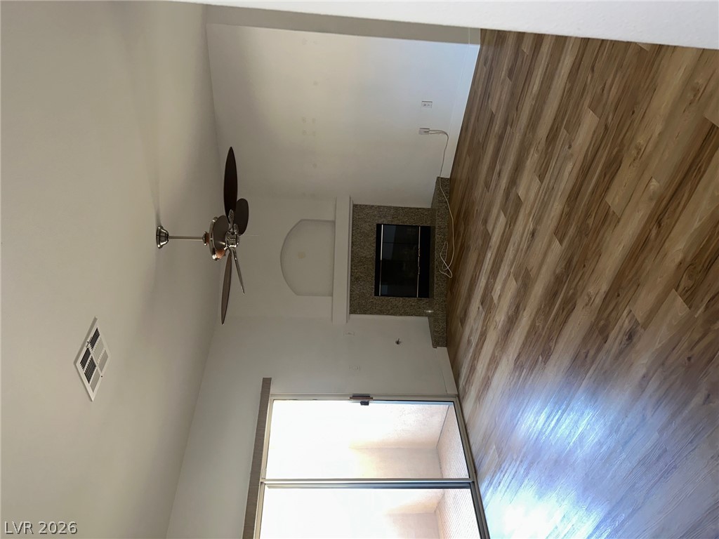 A well-lit spacious living area features ceiling fan and prominent fireplace.
