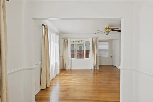 a view of an empty room with window and wooden floor