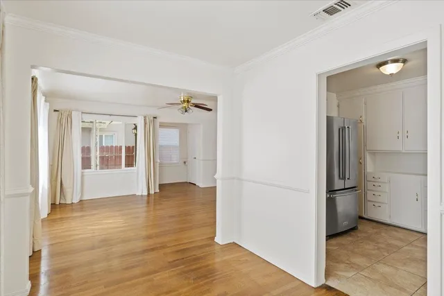 an empty room with wooden floor and a kitchen