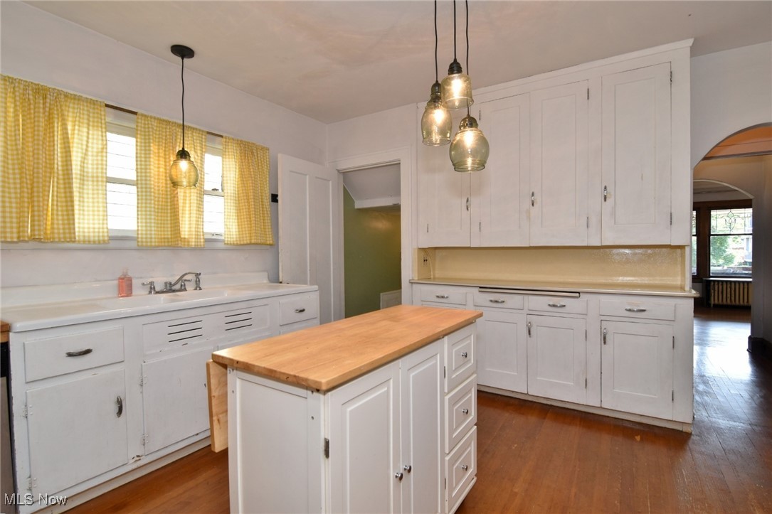17930 Rosecliff Road Cleveland, OH 44119 - Photo 20 of 50 Kitchen featuring arched walkways, butcher block countertops, white cabinetry, wood finished floors, and hanging light fixtures