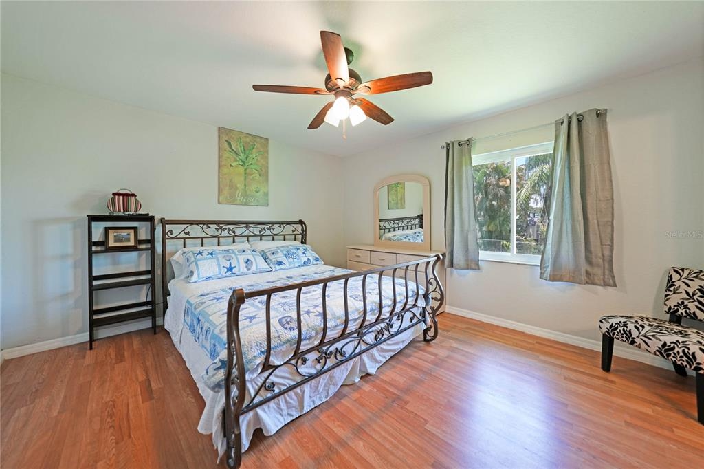 590 Ridgewood Street Northwest Port Charlotte, FL 33952 - Photo 15 of 32 a bedroom with a bed and wooden floor