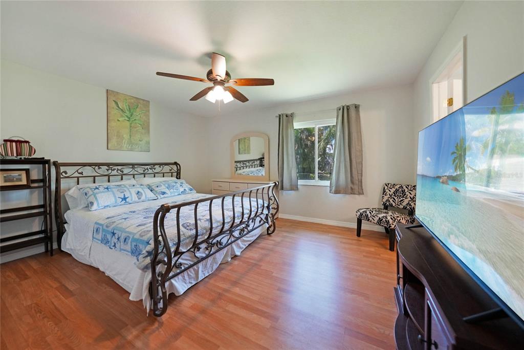 590 Ridgewood Street Northwest Port Charlotte, FL 33952 - Photo 16 of 32 a spacious bedroom with a bed and a chandelier