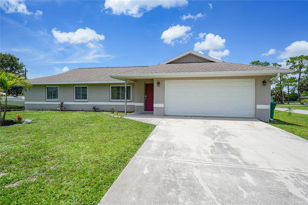 590 Ridgewood Street Northwest Port Charlotte, FL 33952 - Photo 2 of 32 a front view of a house with a garden and yard