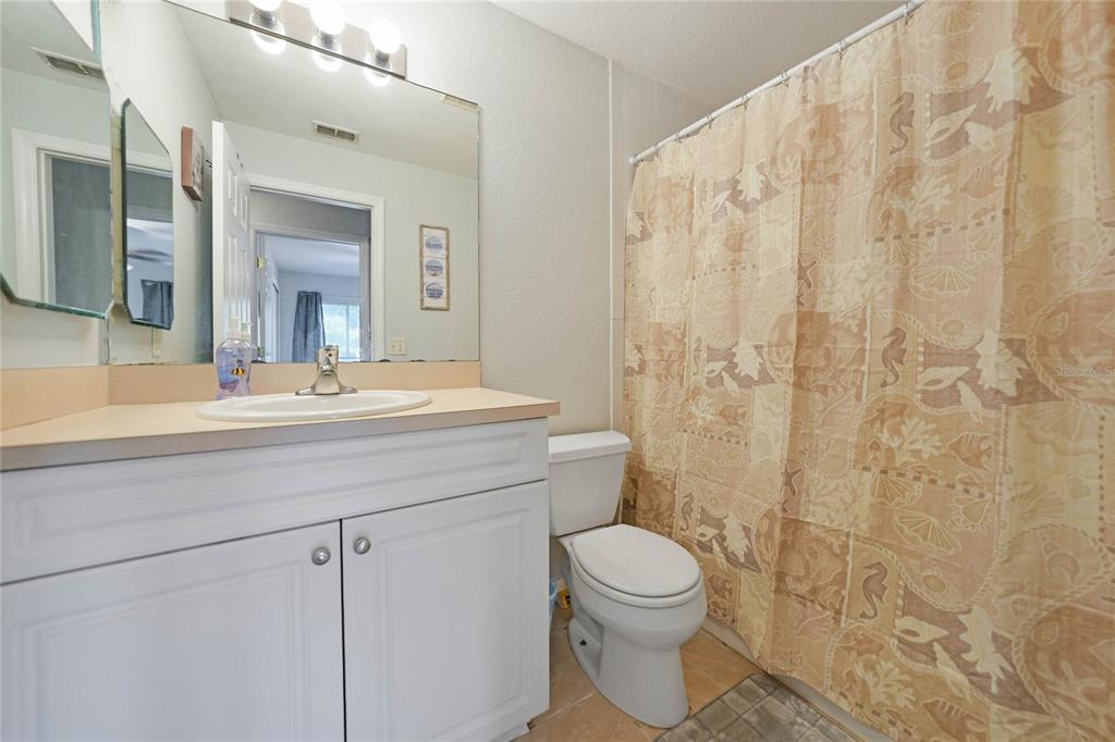 590 Ridgewood Street Northwest Port Charlotte, FL 33952 - Photo 22 of 32 a bathroom with a toilet a sink a shower and a mirror