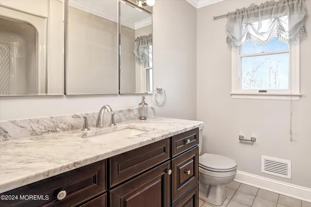 a bathroom with a granite countertop sink a toilet and a mirror