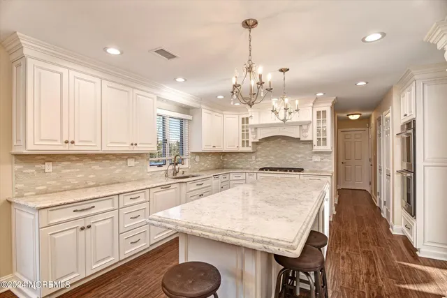 a kitchen with kitchen island granite countertop a stove a sink a center island and cabinets